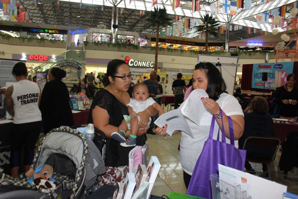 Photo of Terry Naputi, ​Guam CEDDERS Reseach Associate,​ assisting​ a parent complete the Ages & Stages Questionnaire​ (ASQ).