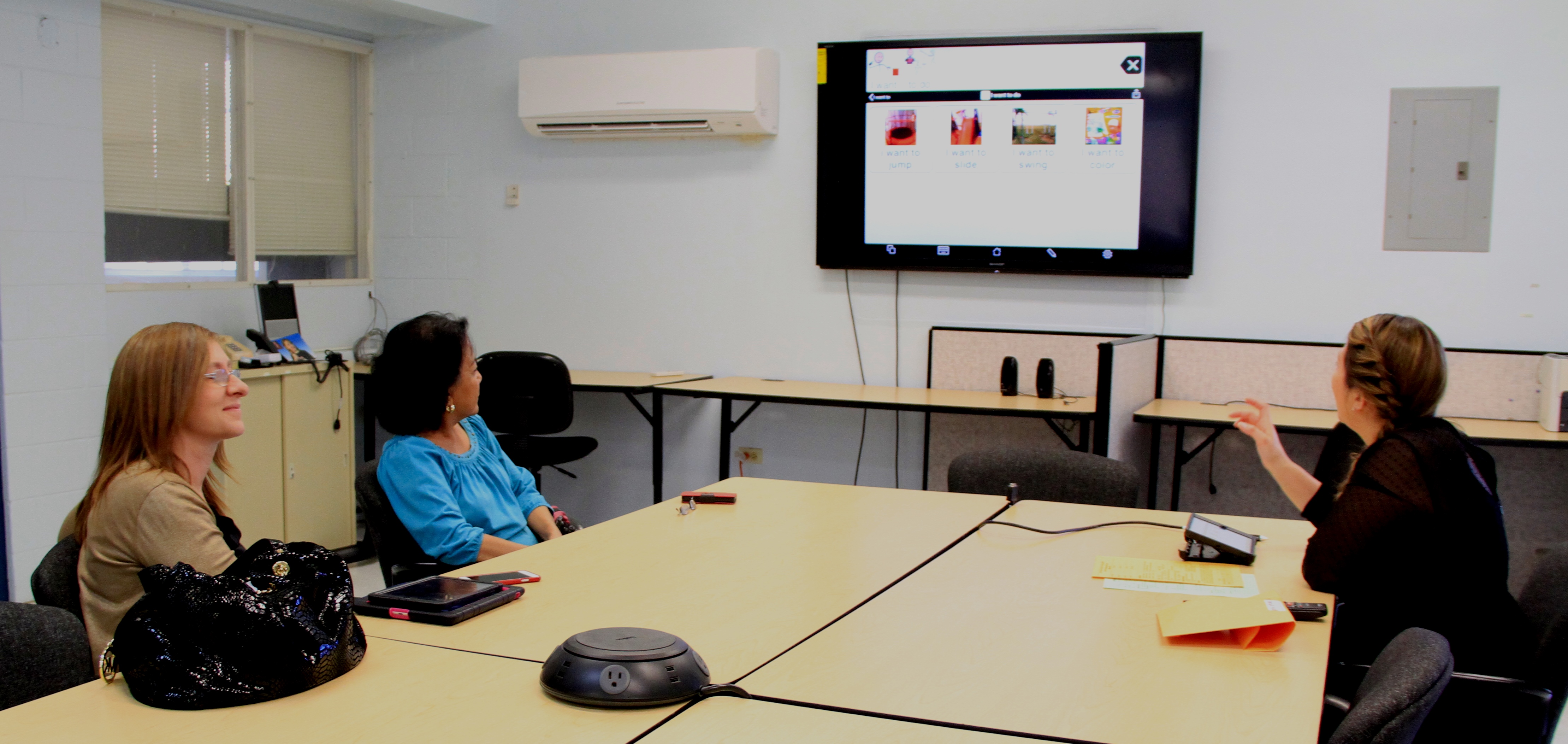 Carla Torres, ATP, Assistive Technology and Special Projects Coordinator, GSAT (Right) demonstrated a Speech and Communication App, "Proloque2Go" to {bottom, L-R) Paola Agostini, parent and Liz Napoli, Speech Therapist, Guam Department of Education on January 14, 2016.