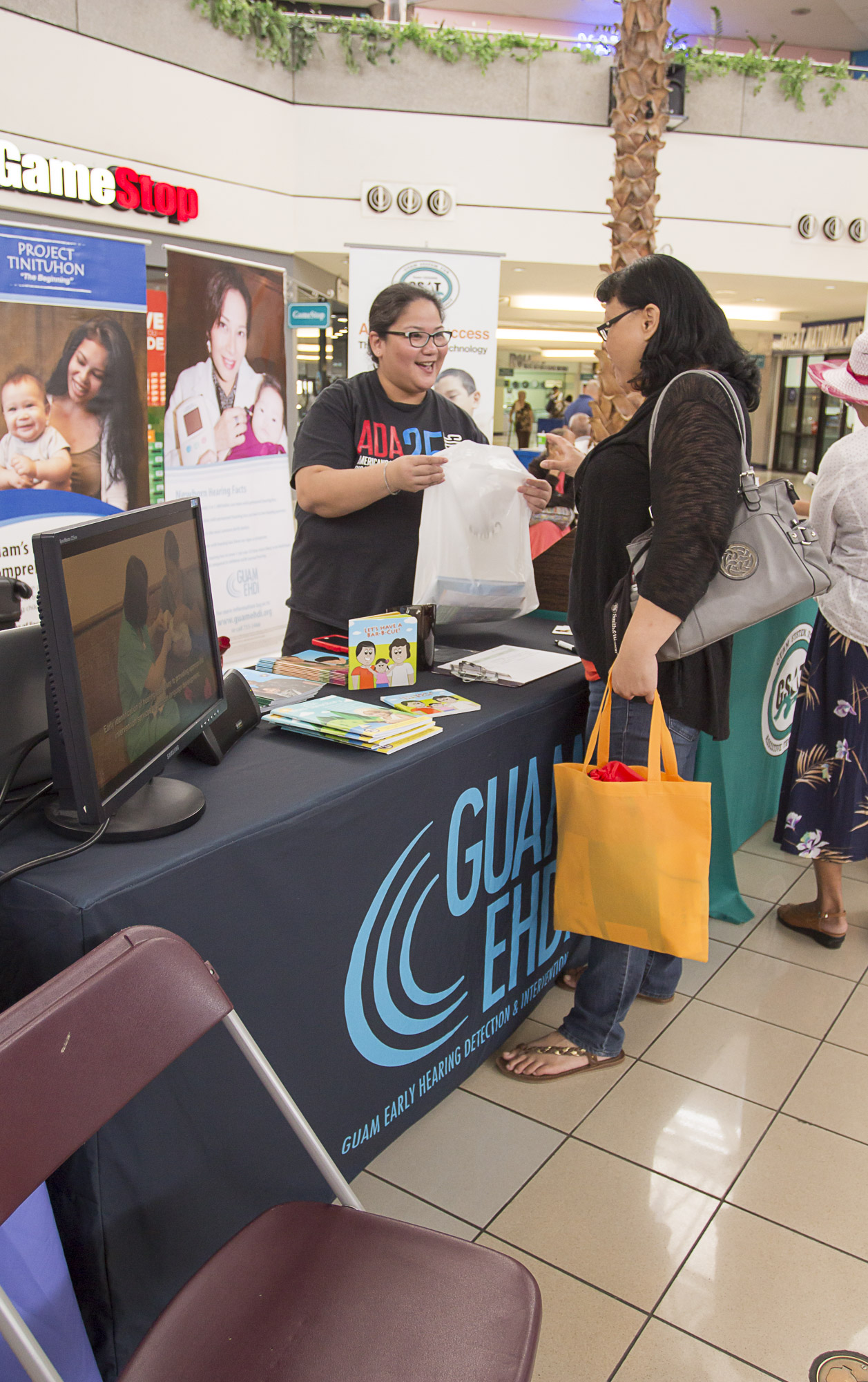 Vera Blaz, Guam CEDDERS Training Associate (left), distributed information on Project Tinituhon and Guam EHDI to a visitors during the Better Speech and Hearing Fair at the Micronesia Mall Center Court on May 7.