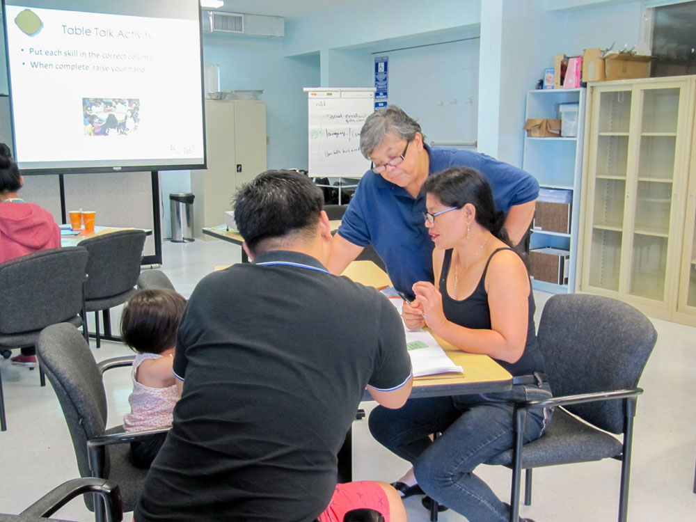 Elaine Eclavea (back), Guam CEDDERS Consultant, speaking to a mother and father.